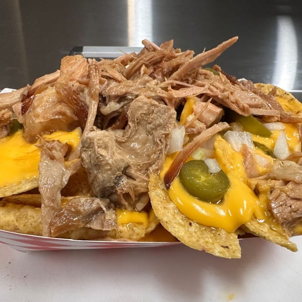 A close-up of Habana Cuba Restaurant's loaded nachos with shredded pork, melted cheese, jalapeños, and onions.